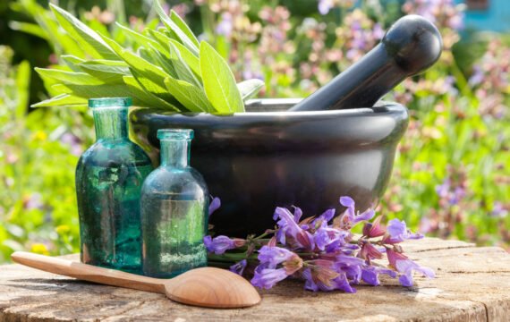 Mortar with sage herbs, glass bottles of essential oil Black mortar with sage herbs, glass bottles of essential oil outdoors. Herbal medicine.